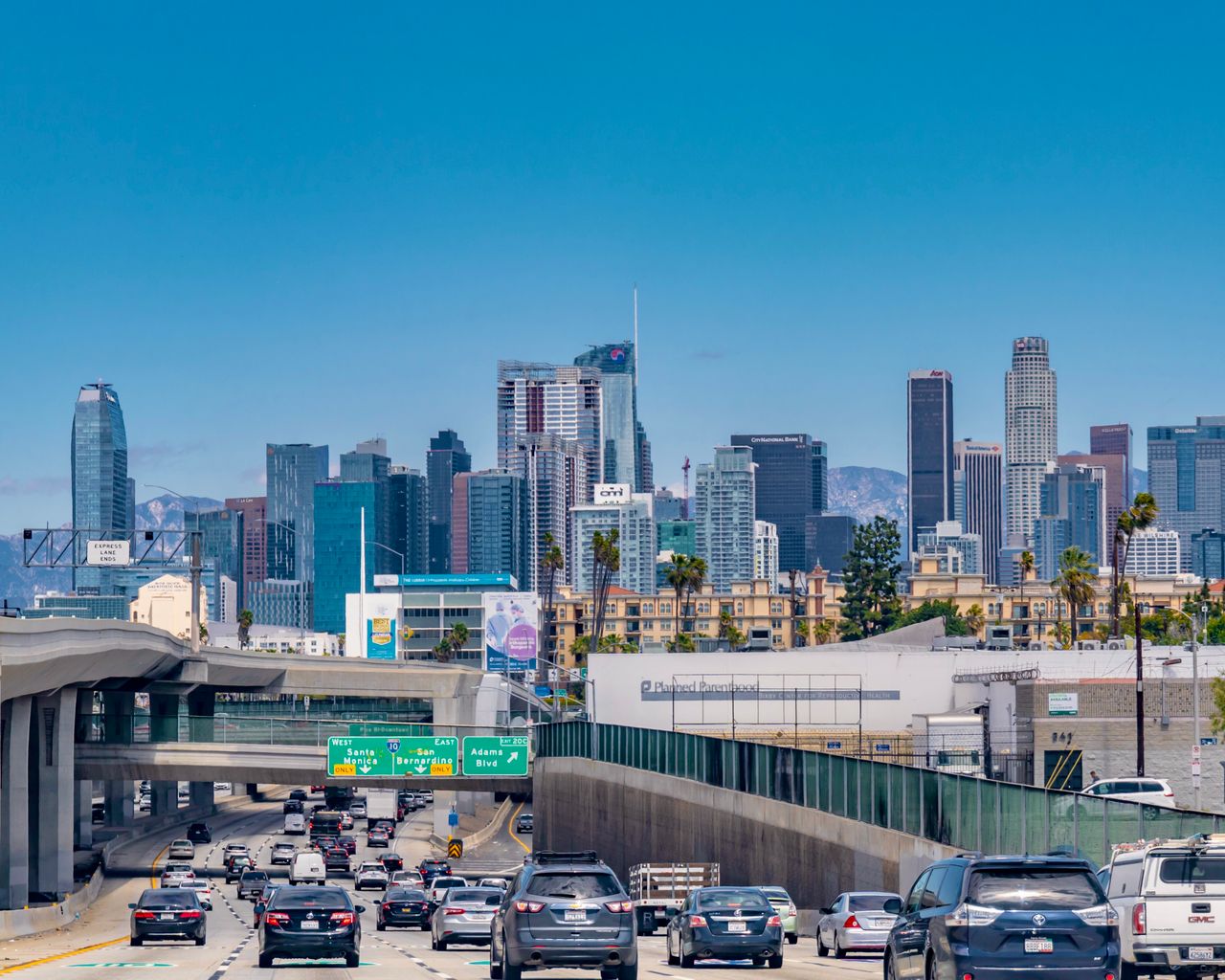 Downtown Los Angeles skyline with busy freeway traffic on a sunny day.